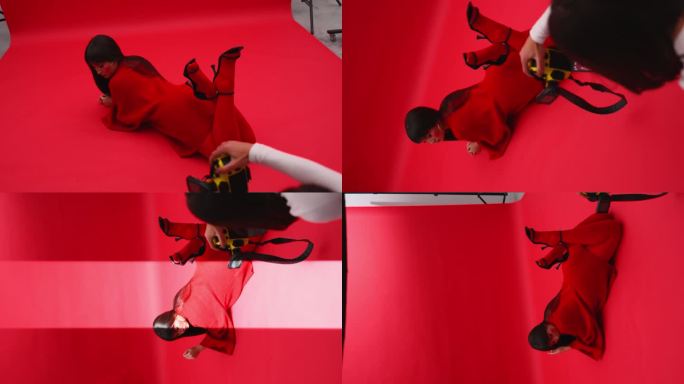 一名女摄影师在摄影棚里以红色背景拍摄身穿红色毛衣的亚洲模特。360度摄像机旋转