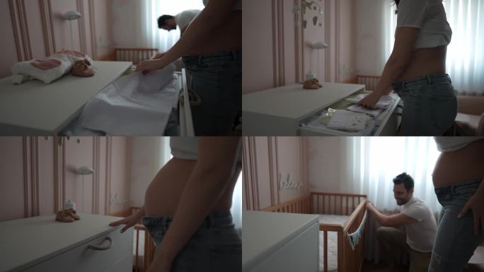 一对怀孕的夫妇在家里的育儿室的婴儿床上挂了一个装饰品