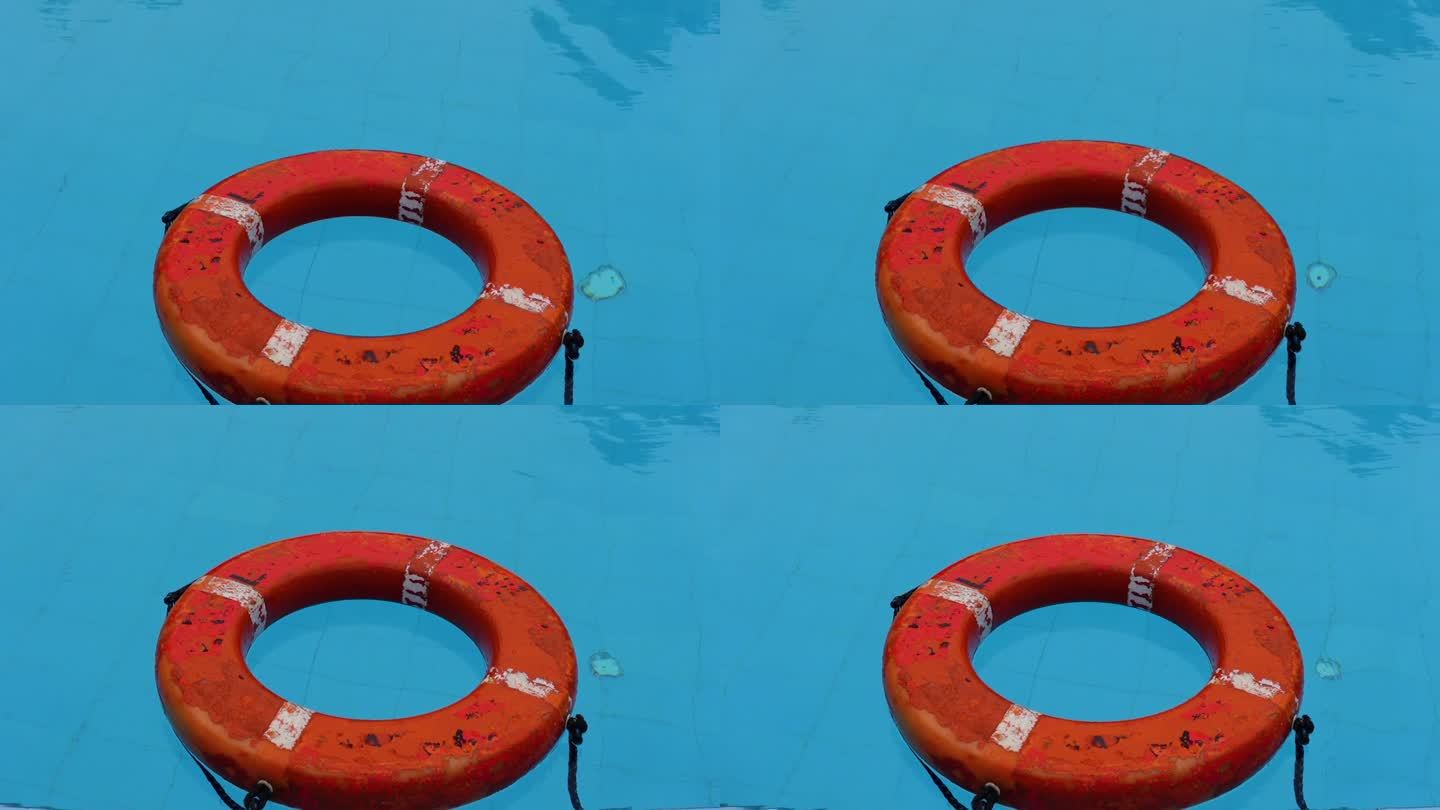 一个旧的救生圈漂浮在游泳池的蓝色水面上。