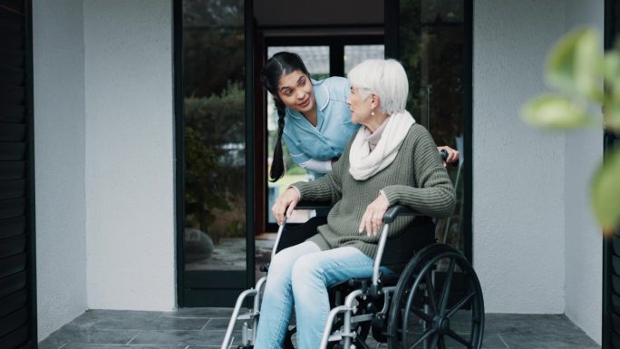 老年妇女，轮椅支持和护士帮助的善良和照顾者在养老院外。关怀、微笑与残疾人一起愉快地交谈和专业护理