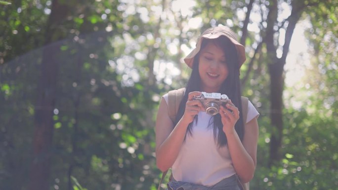 一位女士喜欢在风景优美的森林里徒步旅行，同时被大自然的美景所包围，用她的相机捕捉瞬间