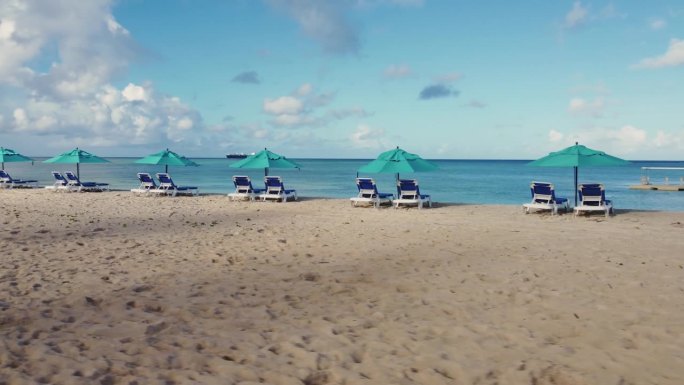在一个晴朗的早晨，低角度无人机拍摄了沙滩椅和遮阳伞