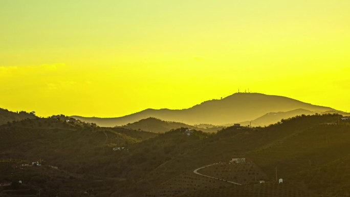 金色的日出越过丘陵景观，群山的剪影，宁静而平静的清晨