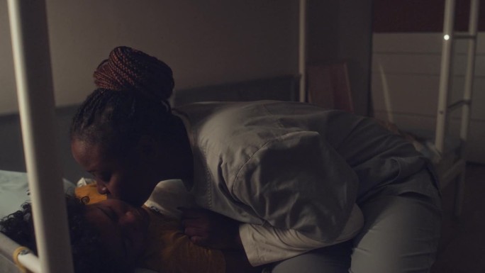 非裔护士在晚班后亲吻熟睡的孩子