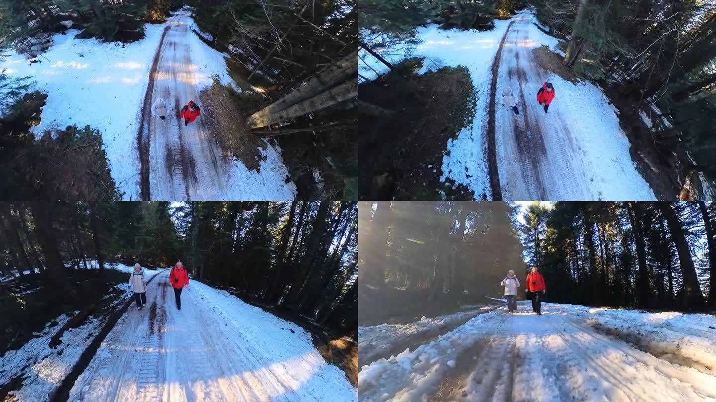 一对成年夫妇在冬天的雪山森林里散步。