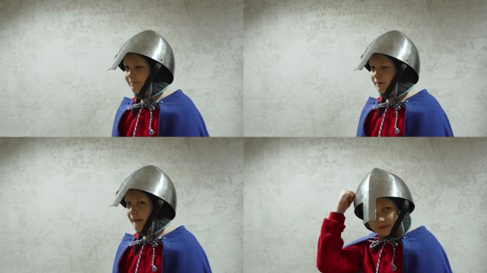 戴着铁骑士头盔的孩子的肖像，男孩敲着头盔，中镜头。