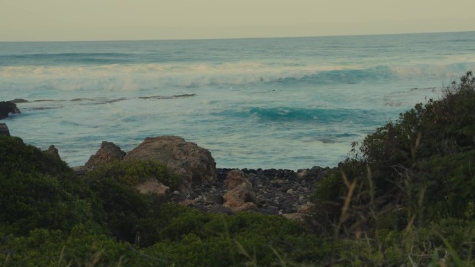 在瓦胡岛的卡埃纳角，滚滚的蓝绿色海浪穿过悬崖上的沟壑，冲击着夏威夷的岩石海岸