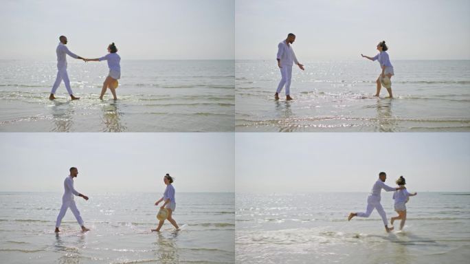 一对夫妇在阳光明媚的海滩上赤脚在水里跑步