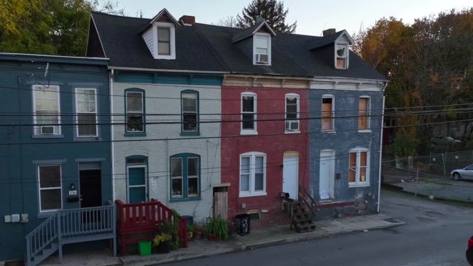 黄昏时分带山墙屋顶的彩色排屋。在美国城市的犯罪猖獗，危险的社区，被木板和废弃的家。天线。