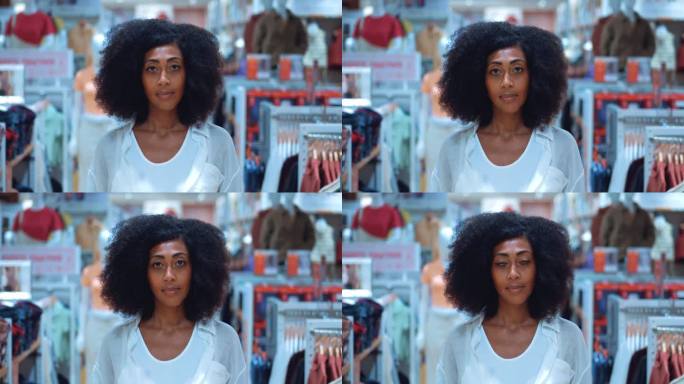 美丽的非裔美国女购物者带着疲惫的表情，面带愉快的笑容，看着镜头，在服装店逛了一天，为自己挑选合适的衣