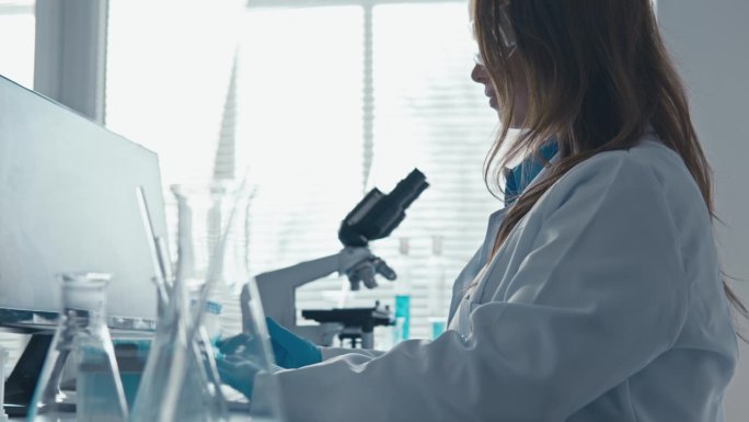 在现代化的实验室里进行医学领域的最新科学研究。从事计算机工作的女科研人员。在研究和发现疫苗和药物的过
