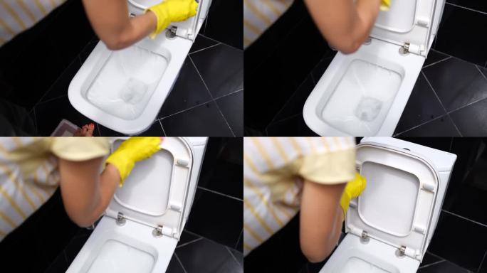 戴着手套的手用毛巾擦拭卫生间马桶的特写