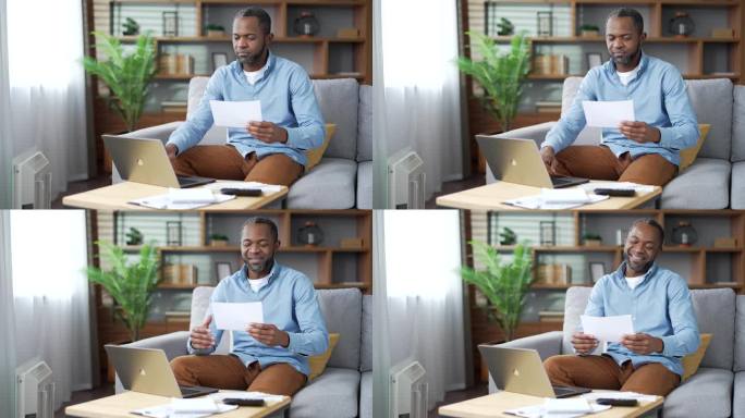 一个成熟的非裔美国人坐在家里的房间里用笔记本电脑申请消费账单