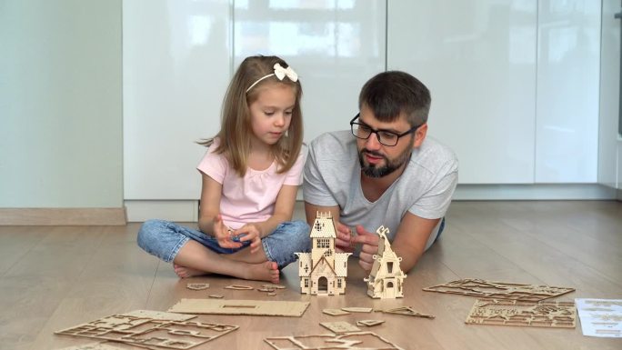 父亲和女儿搭建建筑套装。一家人在玩建筑工具