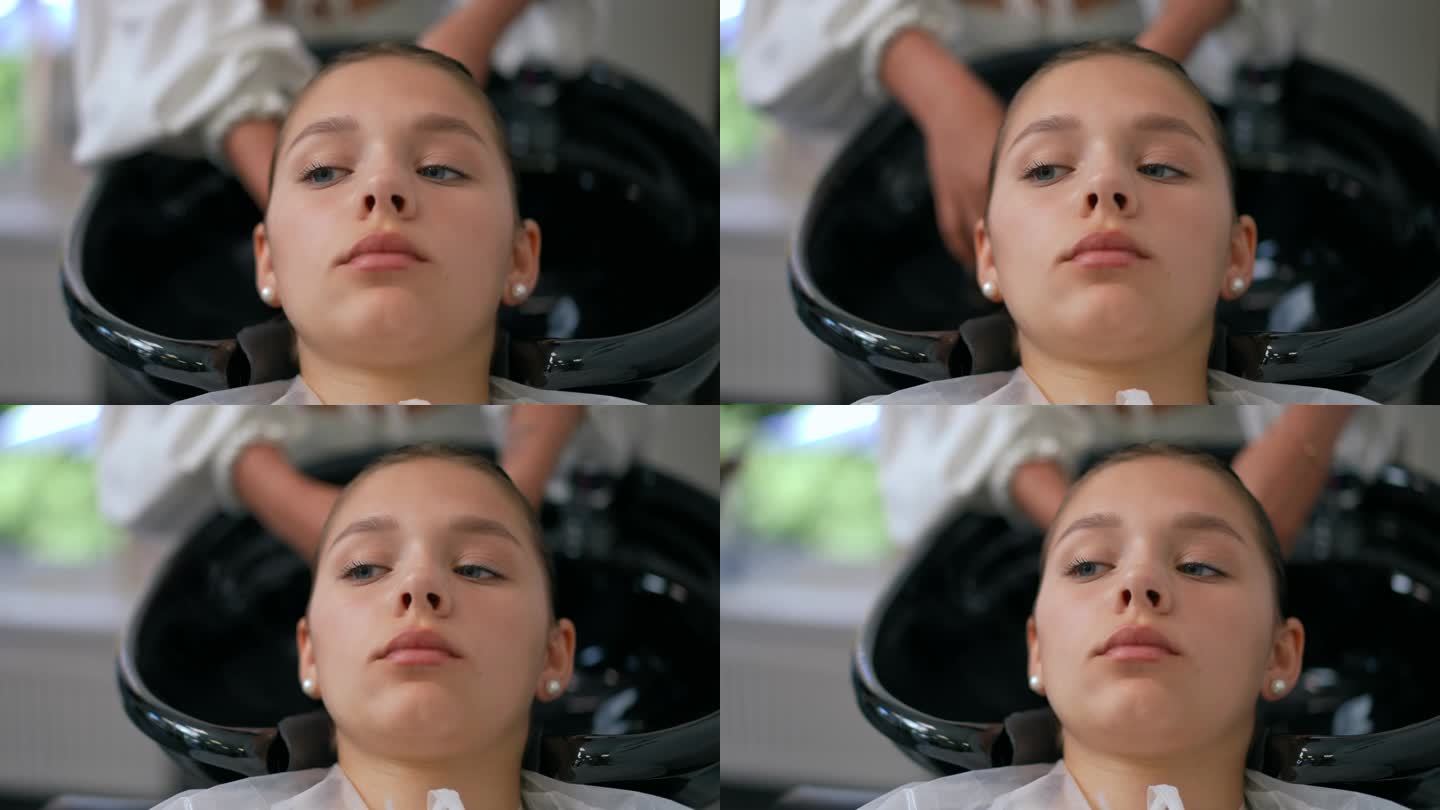 一个女孩正在一家现代美容院洗头。这个女孩正躺在一张带水槽的舒适椅子上。特写镜头。