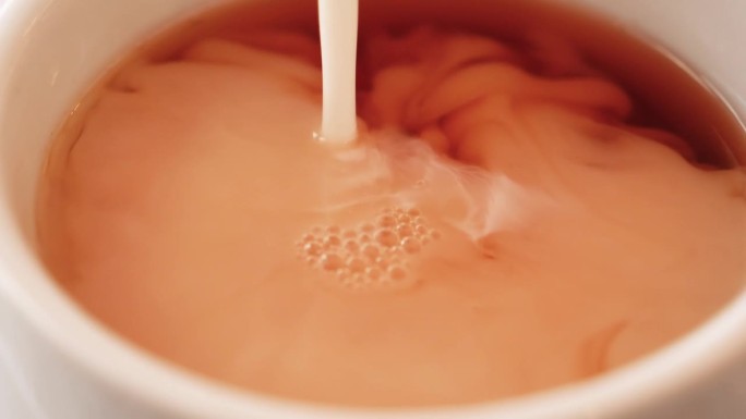 微距镜头捕捉到牛奶倒进咖啡杯，揭示了复杂的细节。简单但视觉上吸引人，描绘了这个日常的美。领袖有创造力
