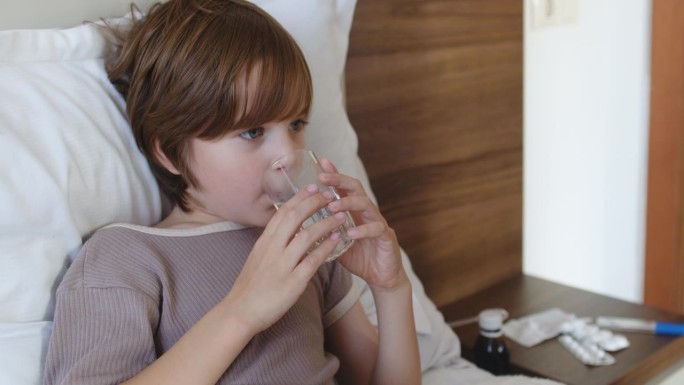 患有感冒、流感、肺炎、病毒或感染的儿童在床上喝水