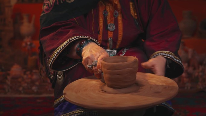 一位身着民族服装的老妇人正在制作一个陶罐。手靠近点。4 k的视频