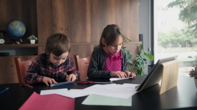 孩子们按照数码平板电脑视频教程中的步骤，用彩色纸做折纸玩具