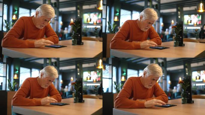 穿着便服的成年老人在咖啡馆的餐桌上玩智能手机