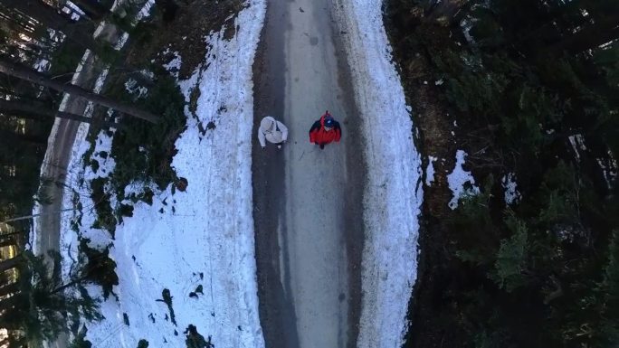 一对成年夫妇在冬天的雪山森林里散步。