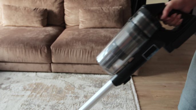 现代公寓中吸尘机吸尘地毯的近照。房屋清洁概念。
