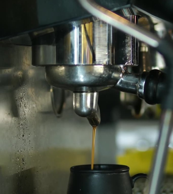 咖啡机正在往杯子里倒咖啡。用咖啡机把咖啡做成杯子，从自动咖啡机里出来的浓缩咖啡。早餐喝饮料