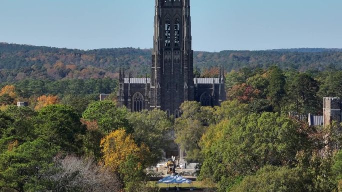 杜克大学教堂。秋季校园绿地上的航拍长镜头，展示了标志性的哥特式石头建筑。