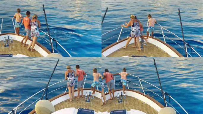 妈妈和她的两个儿子在游艇的船头看海豚