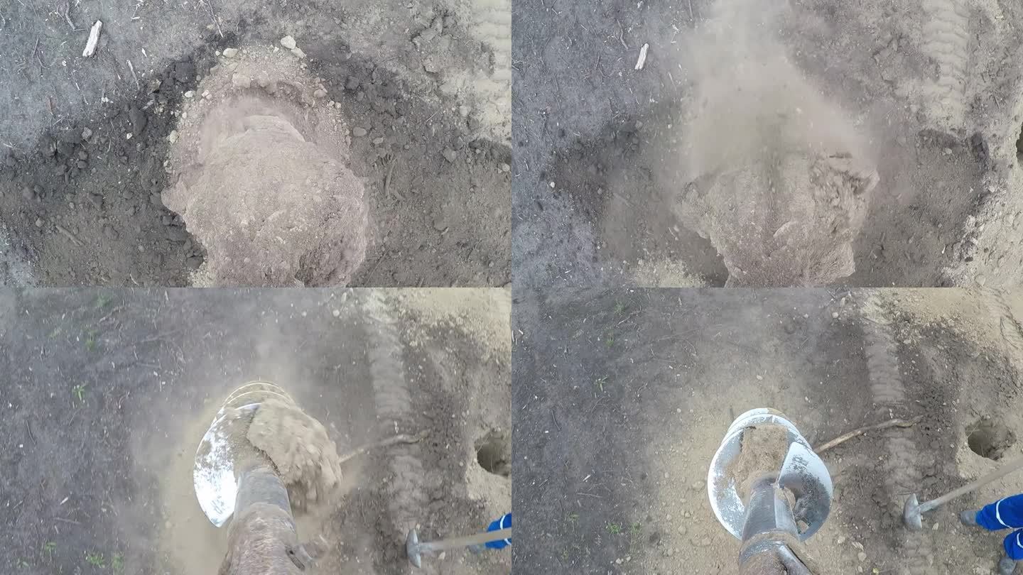 一个钻孔机在地面上钻孔并将泥土从洞中提出来的画面
