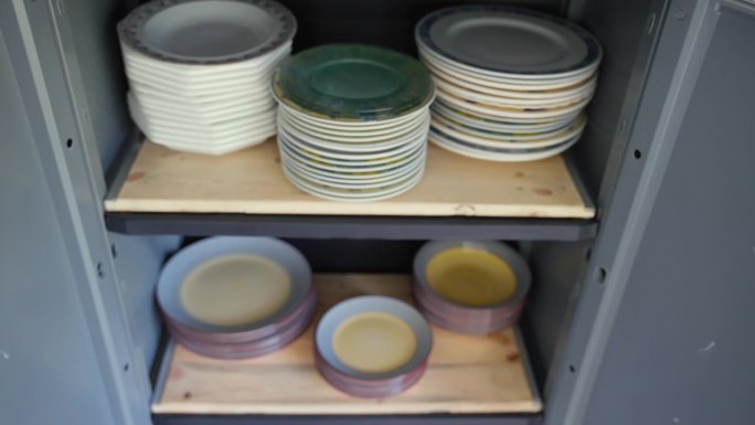 碗柜货架上的各种手工彩绘盘子，家用大小不一的圆瓷盘，集市货架上的老式陶器