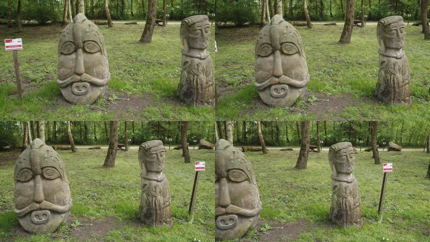 历史悠久的斯拉夫雕塑在自然林地设置。波兰比斯库平郁郁葱葱的绿色公园里的古代石雕。