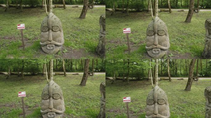 历史悠久的斯拉夫雕塑在自然林地设置。波兰比斯库平郁郁葱葱的绿色公园里的古代石雕。摇上。