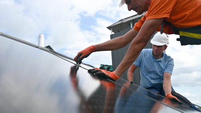工人用内六角键在屋顶上建造光伏太阳能电池板系统。