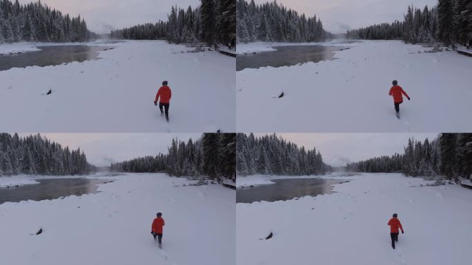 航拍男人艰难地走在新疆喀纳斯河边的雪地里