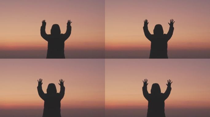 日出时，女人双手合十，做着祈祷的剪影。女性祈祷的生活方式。慢动作视频。女孩双手合十，向上帝祈祷。女孩