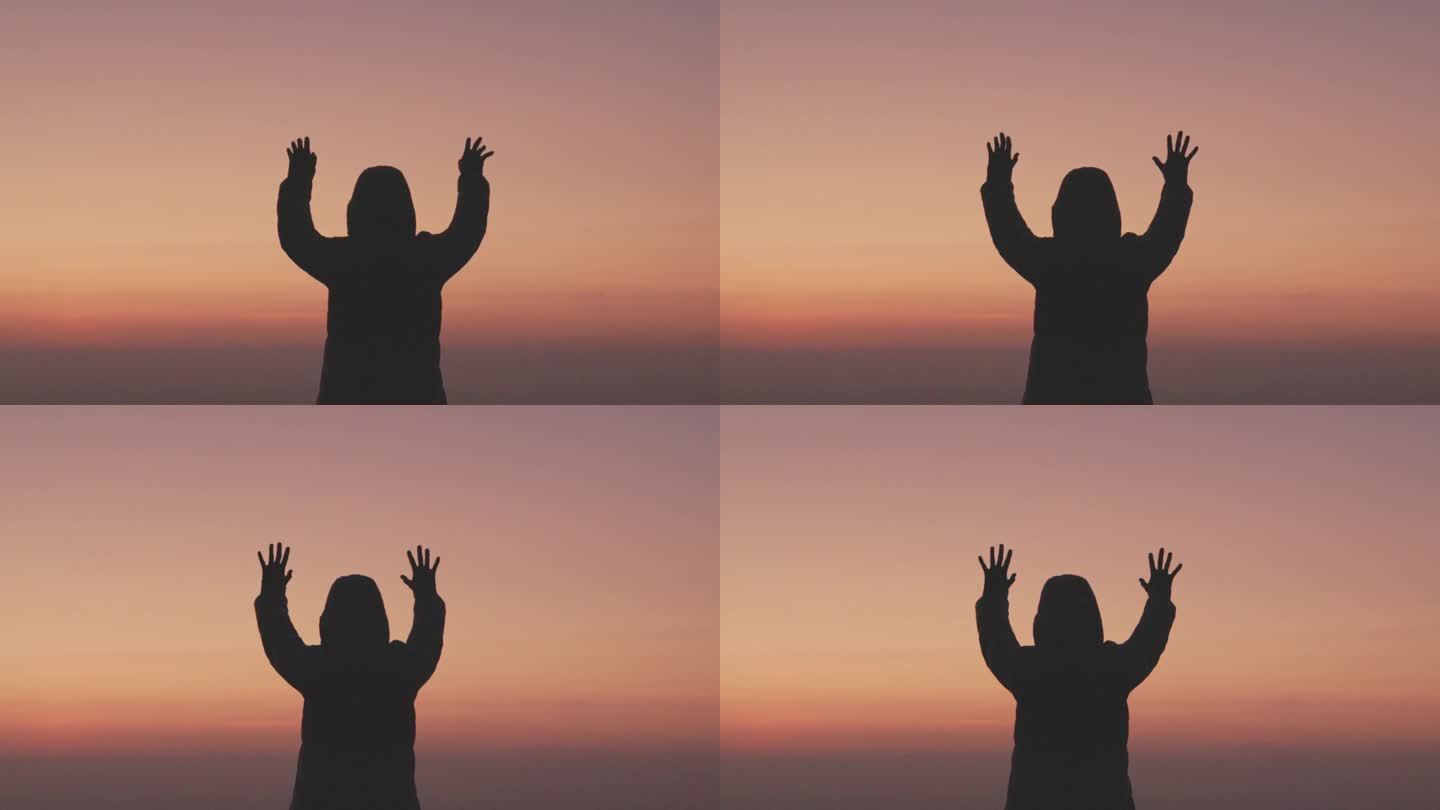 日出时，女人双手合十，做着祈祷的剪影。女性祈祷的生活方式。慢动作视频。女孩双手合十，向上帝祈祷。女孩