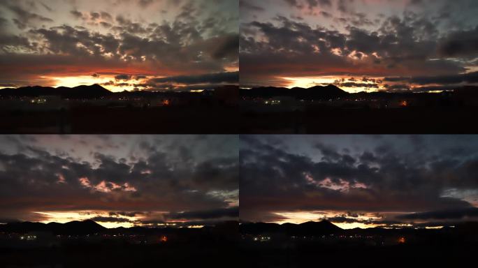 一个神奇的，令人着迷的视频延时美丽的运行云改变颜色和天空在夕阳的光对一个傍晚的城市在灯光的背景下。时