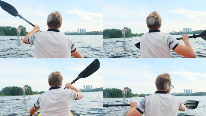划着皮艇的年轻男子跟在划桨板上的女子后面