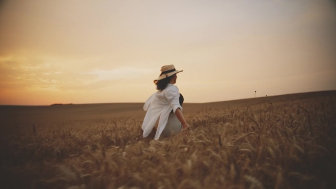 黄昏，一个女人在金色的麦田里快乐地奔跑，拥抱着宁静