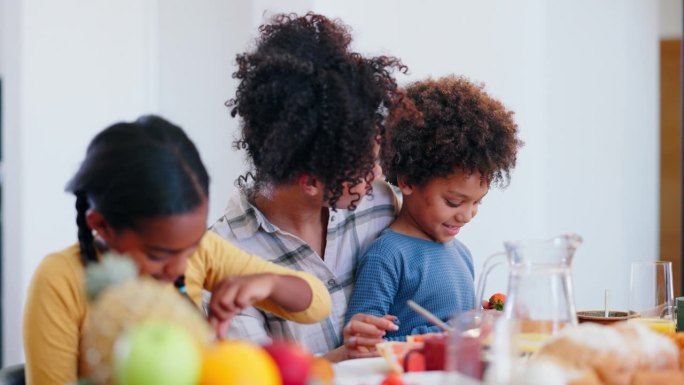 女人、孩子还是交流用饭桌吃饭，午餐或早餐营养用幸福在家。母亲、儿子和孩子们在家里吃早午餐，吃蓝莓、维