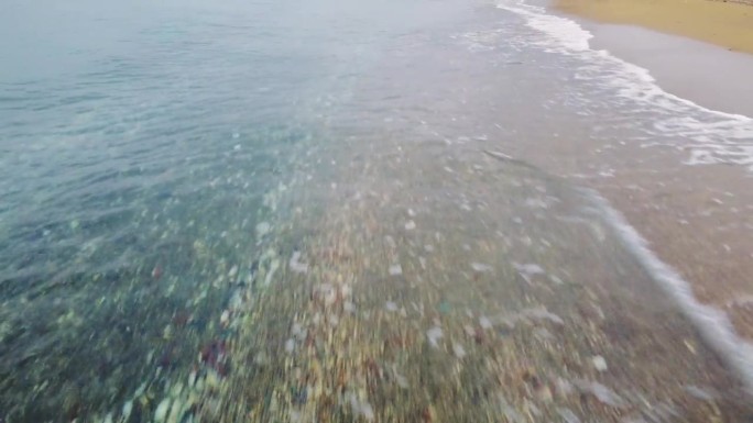 无人机在海滩上滑翔，捕捉日落时的波浪和水。海浪，水的惊人画面。惊心动魄的海浪，海岸线上的海水