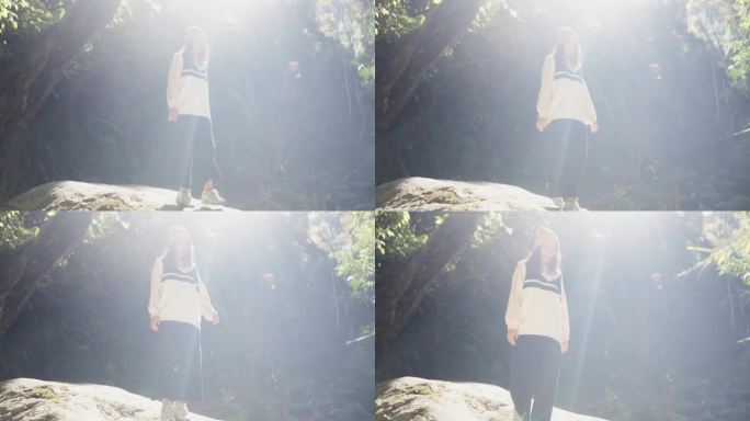 一个亚洲女人在森林里度假时在瀑布边的岩石上散步