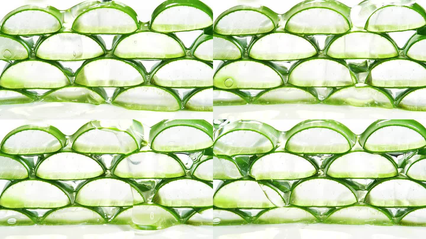 新鲜的绿色芦荟植物切片堆叠在白色背景上的叶子和透明的提取物凝胶流过芦荟成分。芦荟凝胶有用的草药皮肤药