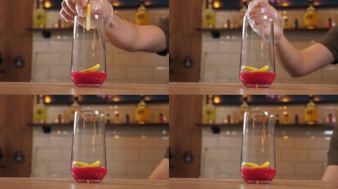 酒保把柠檬片和一杯浆果汁放在一起的特写镜头。