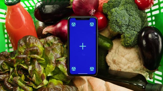 食品购物配送，网上商店应用，智能手机蓝色度键屏，新鲜蔬菜俯视图。在超市购买食品。