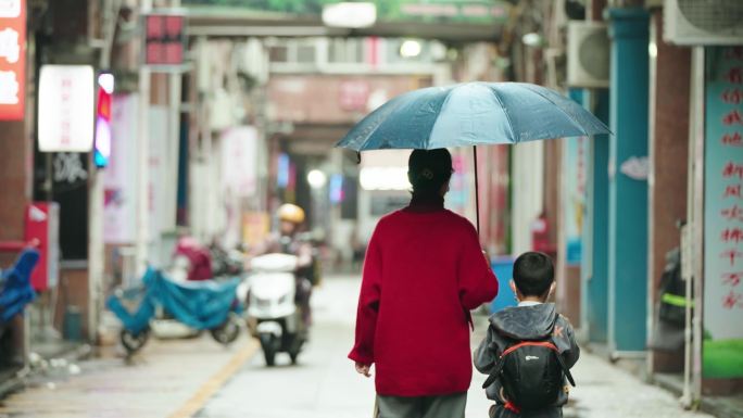 一对母子老街行走背影 妈妈给儿子撑伞