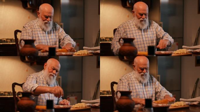 在家庭厨房里准备饺子的过程。一位穿着衬衫、留着胡子的老人在一块木板上用擀面杖擀面。一个男人把面粉撒在