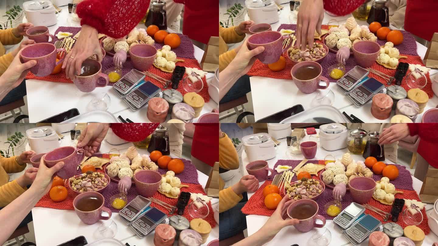单身派对女人的茶话会做按摩蜡烛喝茶聊天坐在桌子旁女孩手拿粉色杯子的特写，不认识的人，甜点和坚果。