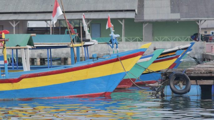 挂着印尼国旗的彩色木制游船停泊在楠榜岛的沿海港口，在海浪中颠簸